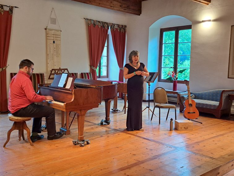 A singer, and a piano player perform music inside the historic Priory in Talloires, also known as the Tufts European Center. 