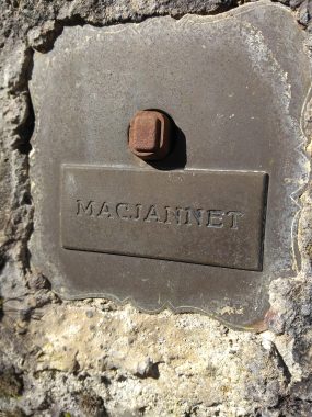 An old doorbell, now rusted, with the word "MacJannet" above it in stone