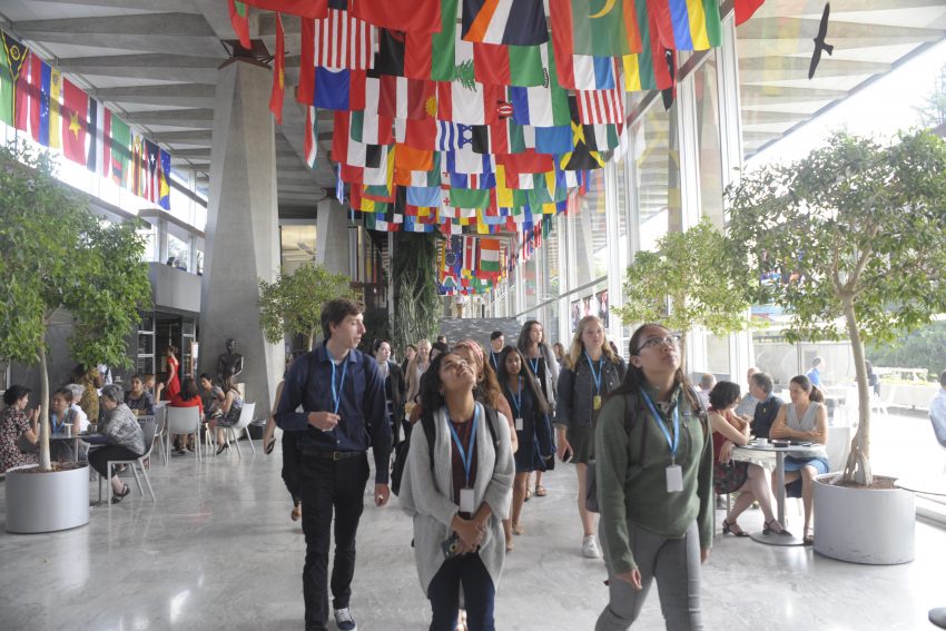 Students looking up at a ceiling of many nations' flags