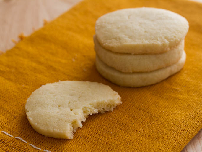 Round, light yellow butter cookies on a wooden countertop